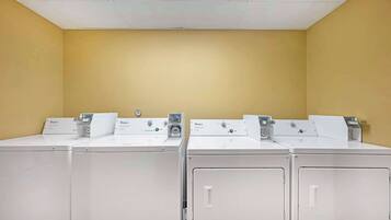 Un lavadero con cuatro lavadoras y secadoras Whirlpool blancas.