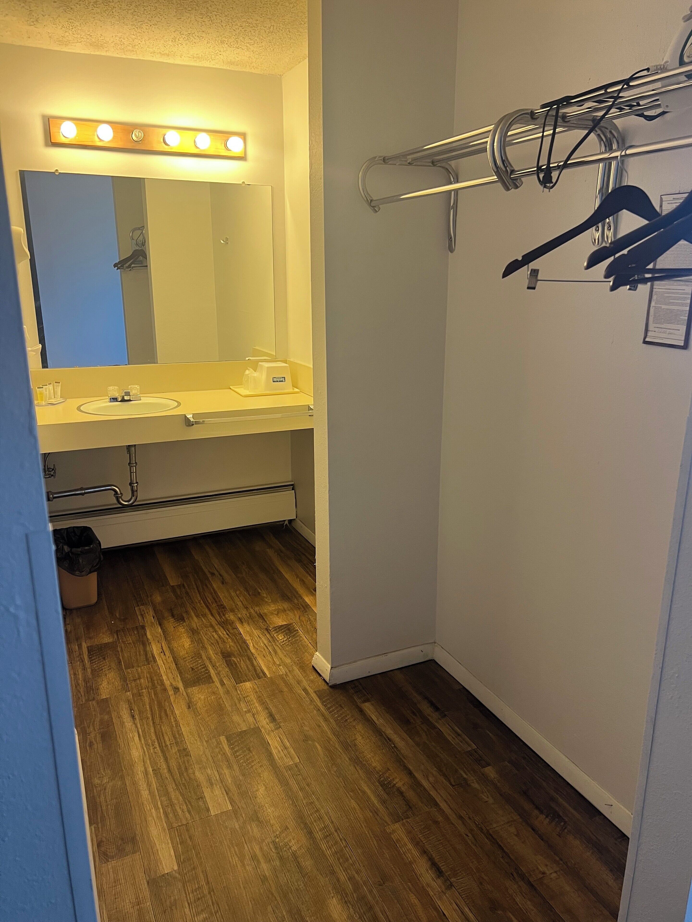 Kylpyhuone, jossa on pesuallas, peili, allaskaappi ja pyyhekoukku.