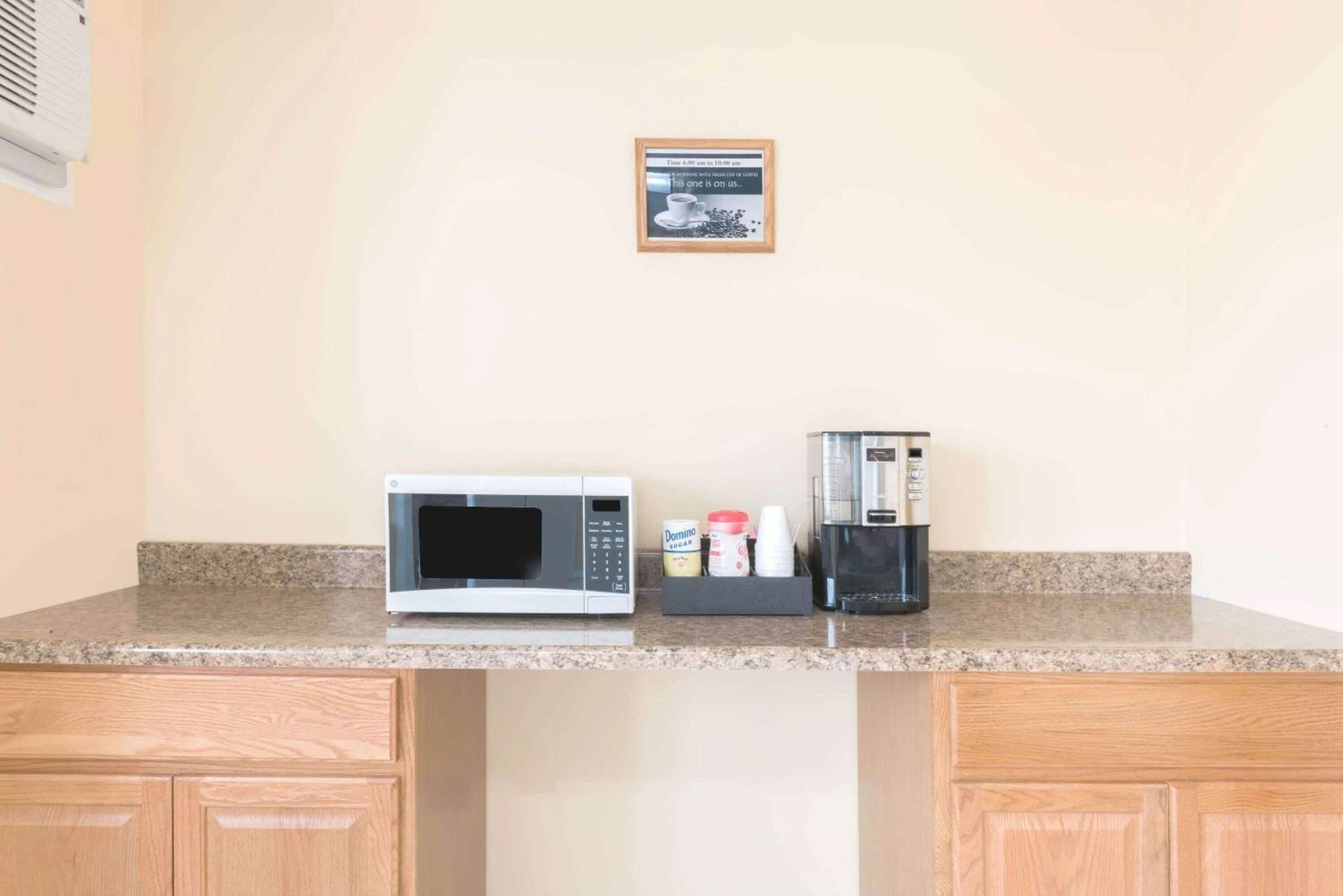 Cucina con forno a microonde, macchina del caffè e un piccolo armadietto.
