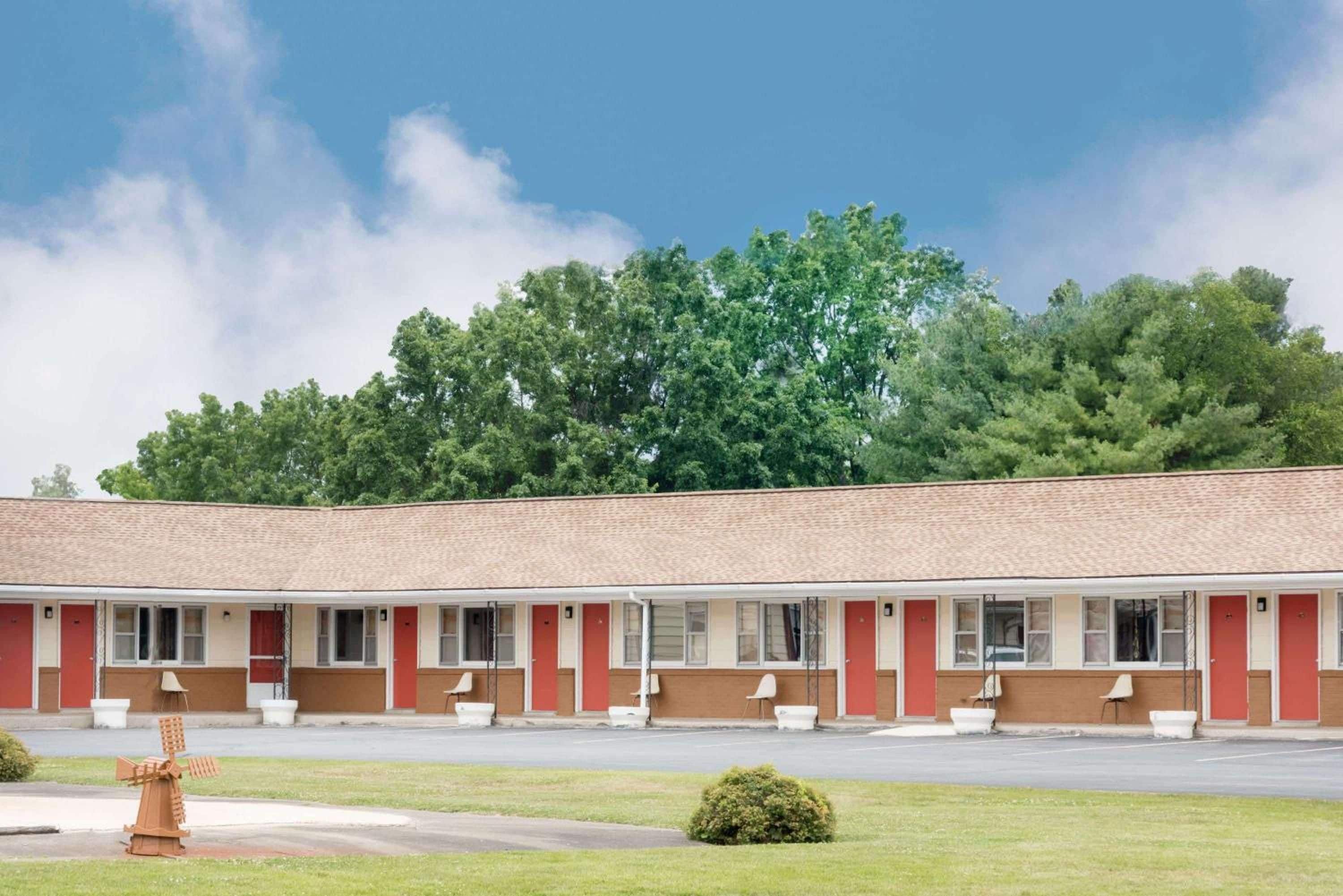 A motel with a row of rooms, a drive-through, and a windmill in the foreground.