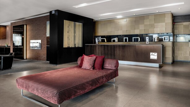 Un moderno vestíbulo de hotel con una recepción, un sofá y un diseño minimalista.