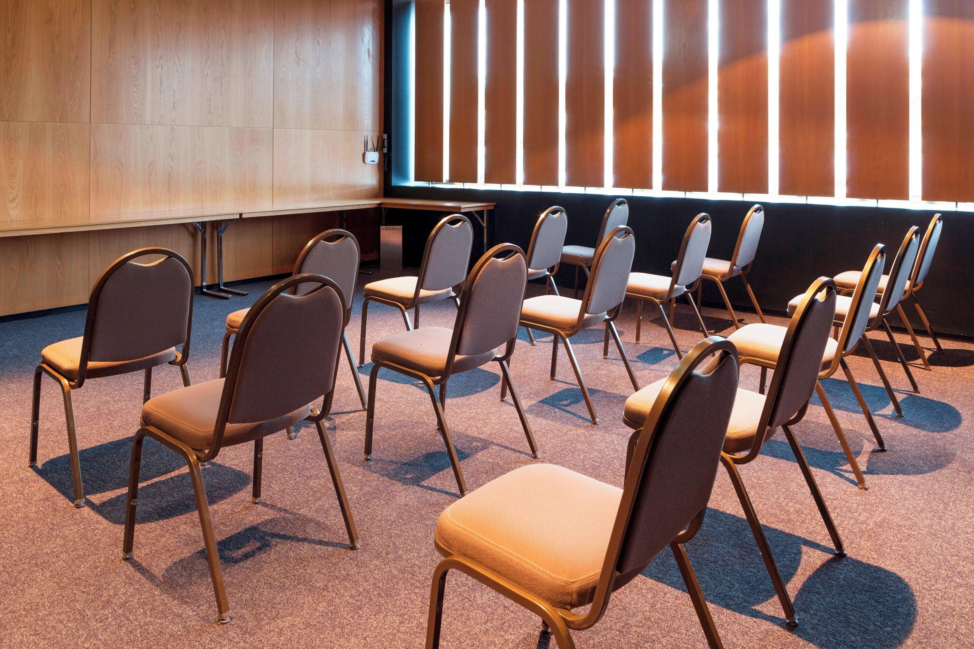 Un salón de conferencias con filas de sillas y una pantalla grande.
