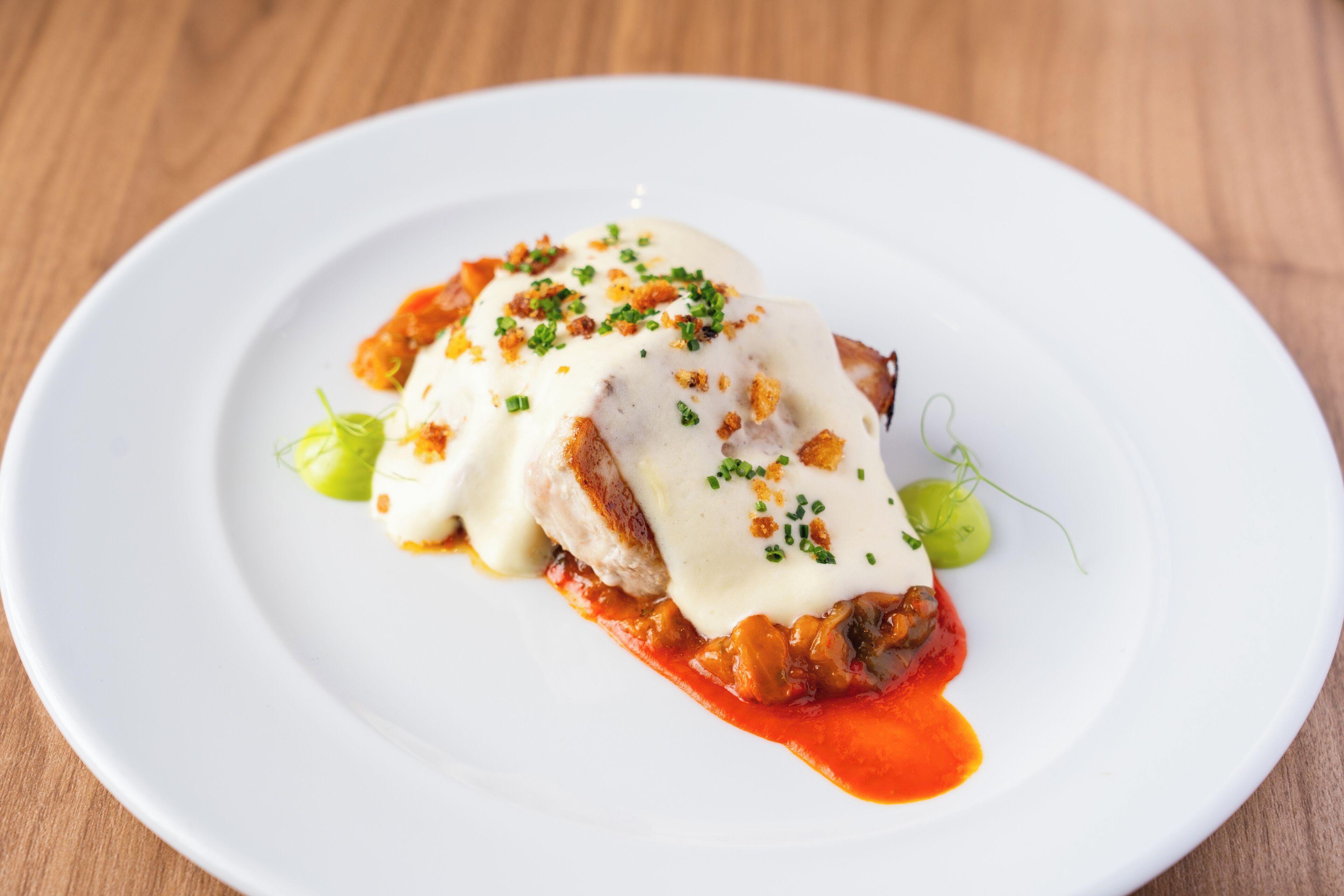 Un plato blanco con un alimento cubierto de salsa y decorado con hierbas verdes.