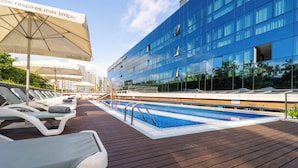 A modern hotel with a swimming pool, sun loungers, and a large glass building. - Abba Playa Gijon Hotel (Gijon)