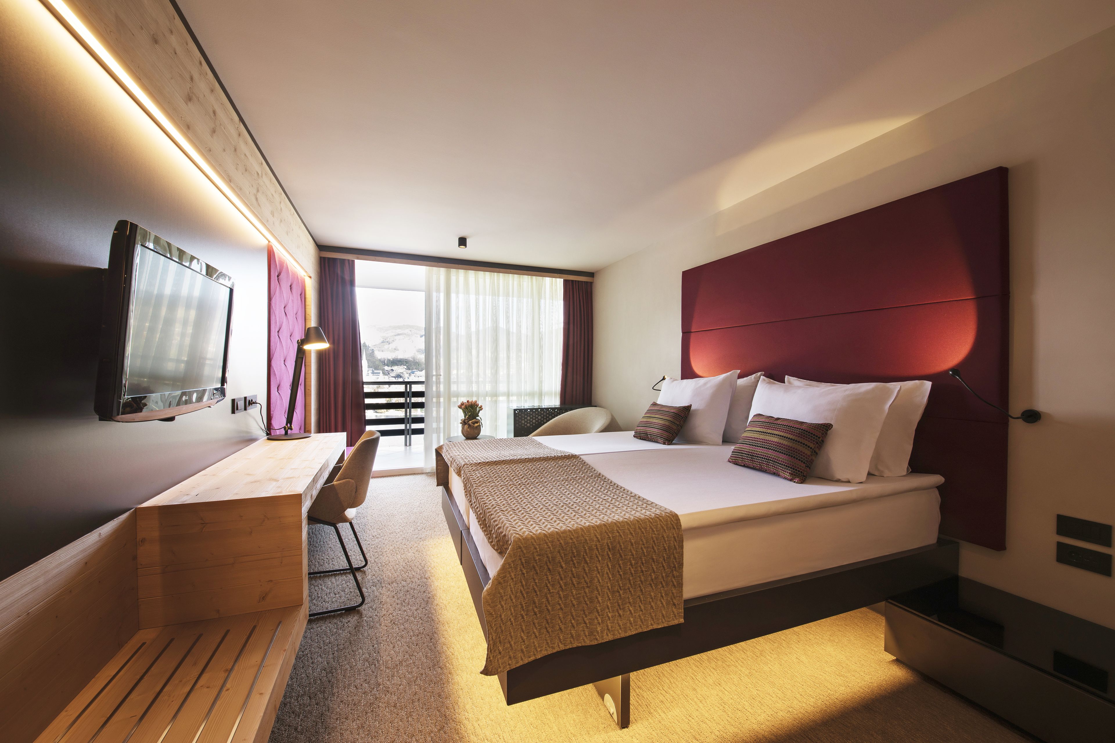 Ein modernes Hotelzimmer mit Bett, Schreibtisch und Stuhl.