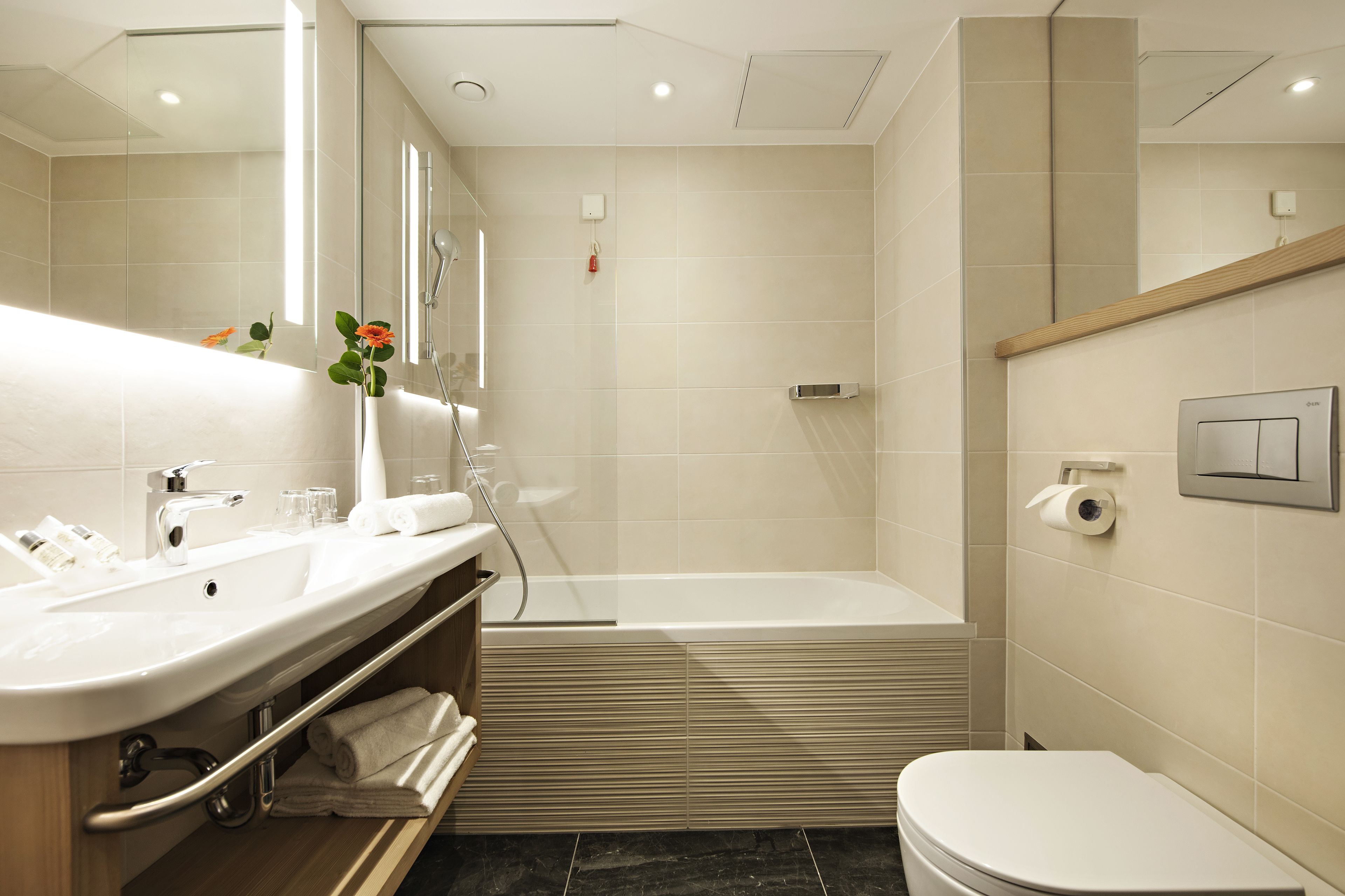 Ein modernes Badezimmer mit Waschbecken, Spiegel, Dusche und Toilette.