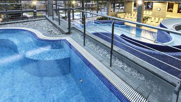 A modern indoor swimming pool with multiple lanes and a seating area with chairs.