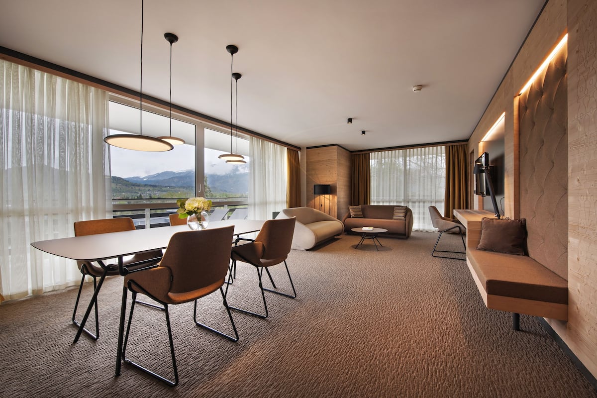 Une chambre d’hôtel moderne dotée d’un coin repas, d’un canapé et d’un téléviseur fixé au mur.