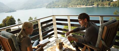 A terrace with wooden furniture, a table with a metal container, and two glasses.