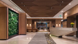 Un moderno vestíbulo de hotel con recepción, zona de estar y un jardín vertical verde.