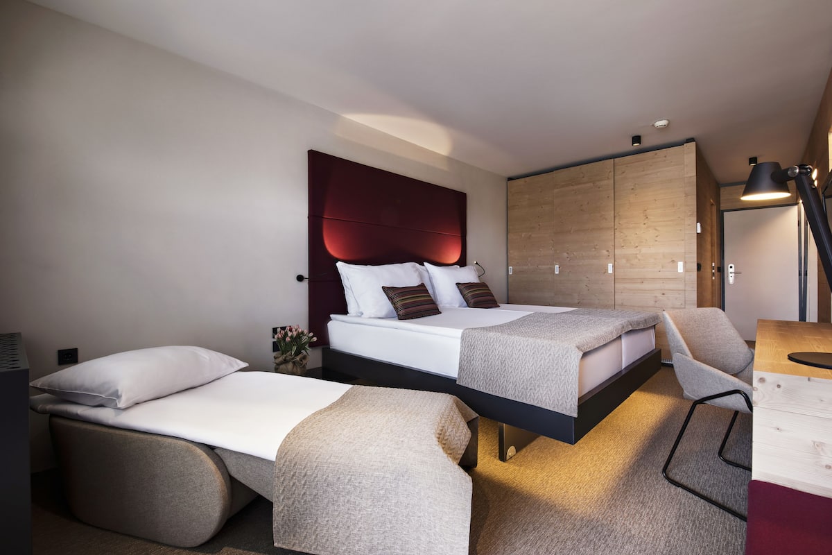 Une chambre d’hôtel moderne, équipée d’un lit, d’un bureau et d’une chaise.