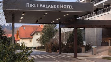 The entrance of Rikli Balance Hotel with a covered walkway and a view of the surrounding buildings.