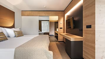 A modern hotel room with a large bed, a small desk, a flat-screen TV, and a wooden accent wall.