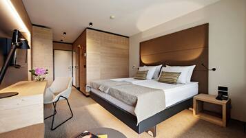 A modern hotel room with a large bed, a desk, and a chair.