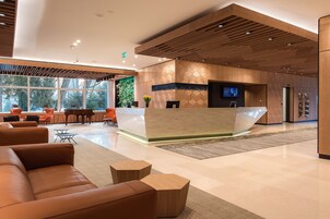 A modern reception area with a wooden reception desk, leather sofas, and a large window offering a view of trees.