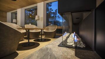 A modern living room with a fireplace, comfortable seating, and large windows.