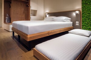 Un dormitorio moderno con dos camas individuales, cabeceros de madera y una pared verde.