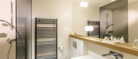 A modern bathroom with a glass shower enclosure, a toilet, and a sink with a mirror above.