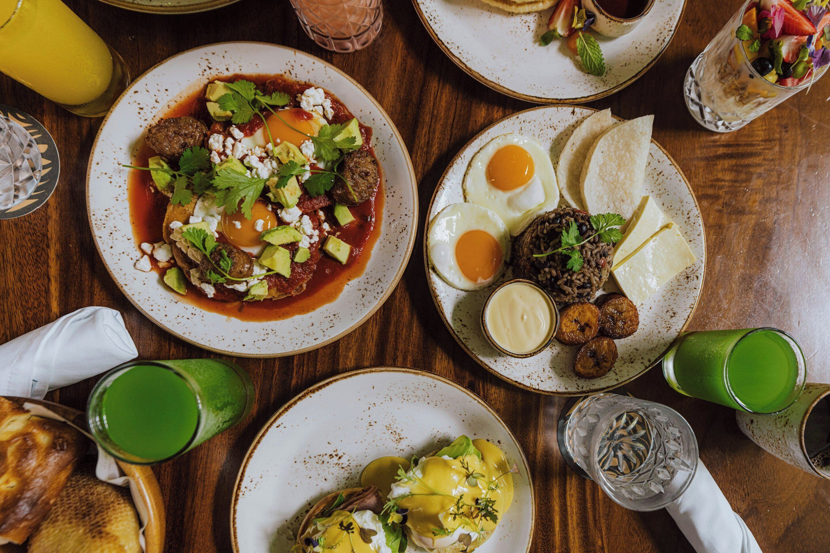 Una mesa con diversos platos, como albóndigas, huevos y una bebida verde.