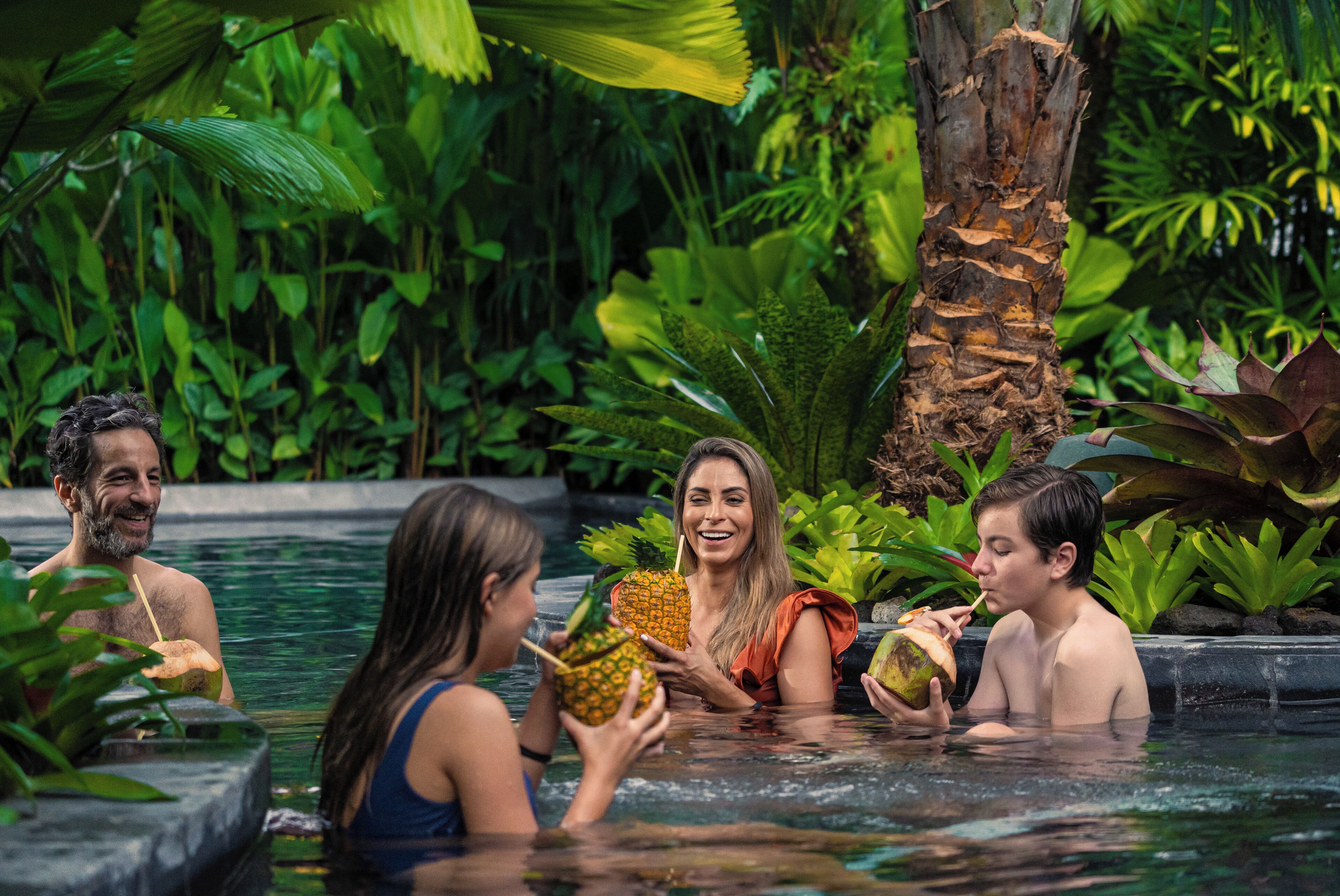 Un grupo de personas en una piscina rodeada de abundante vegetación.