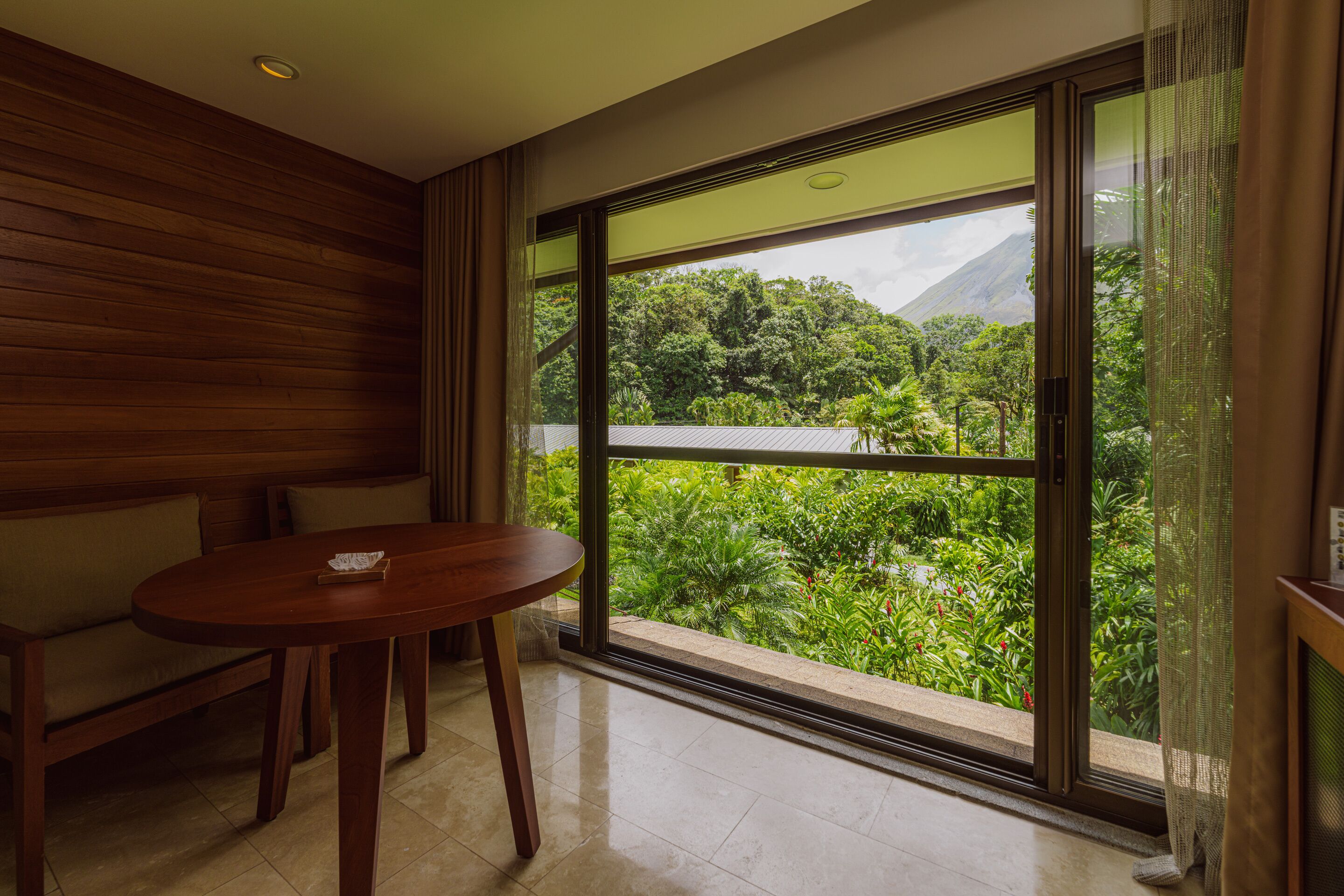 Habitación con un amplio ventanal que ofrece vistas de exuberante vegetación y una montaña.