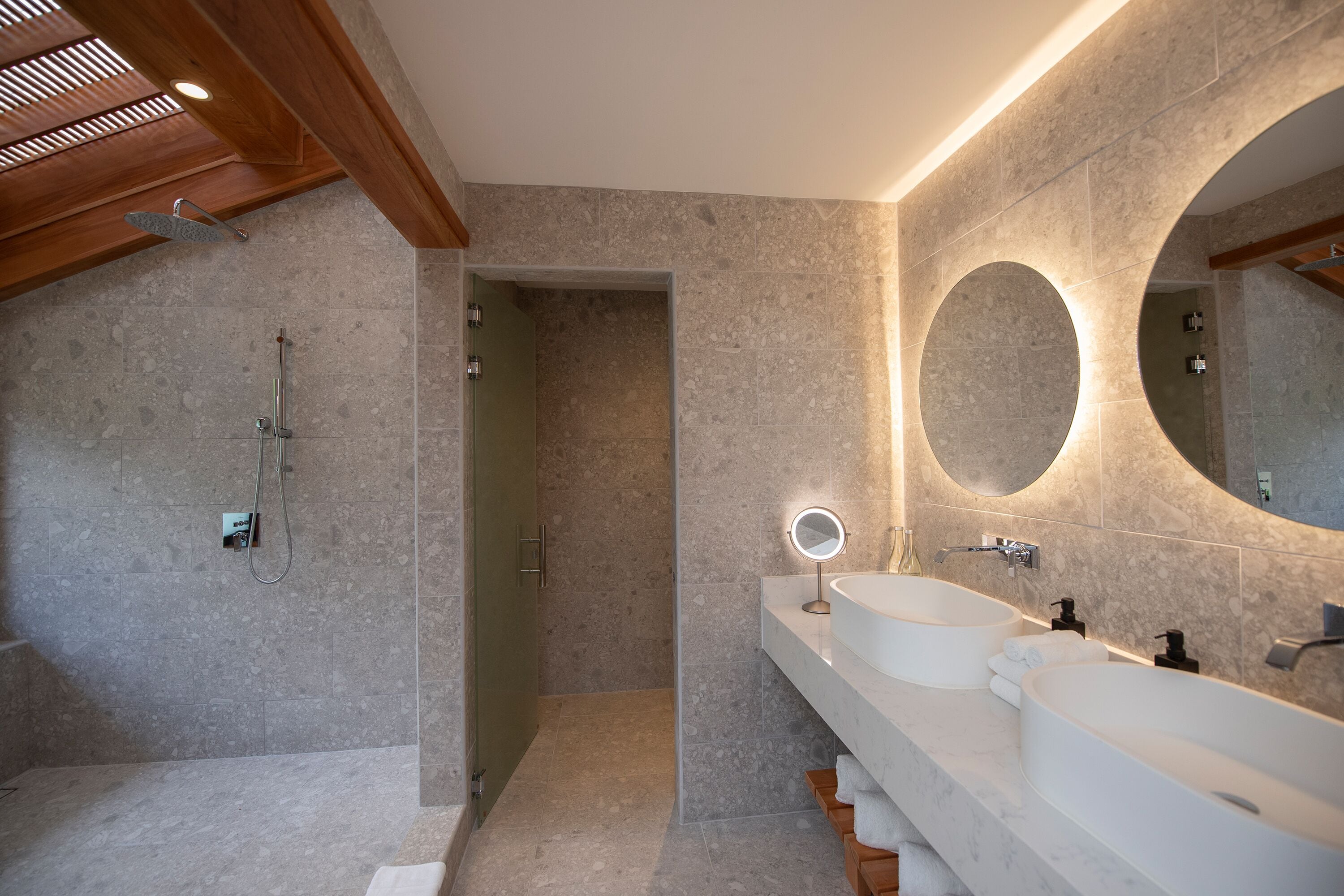 Un baño moderno con dos lavamanos, un espejo grande y una ducha.
