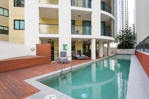 Una piscina al aire libre, sillones reclinables de piscina