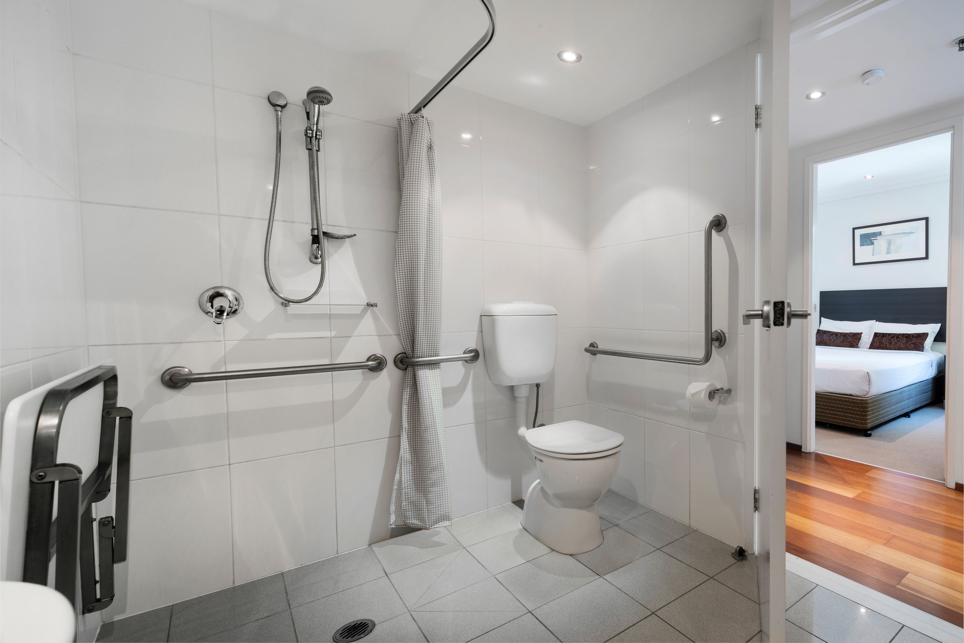 Un baño moderno con ducha, inodoro y barras de apoyo.