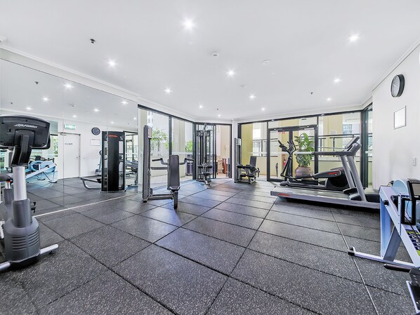 Un gimnasio con diversos equipos de ejercicio, como cintas de correr y máquinas de pesas.