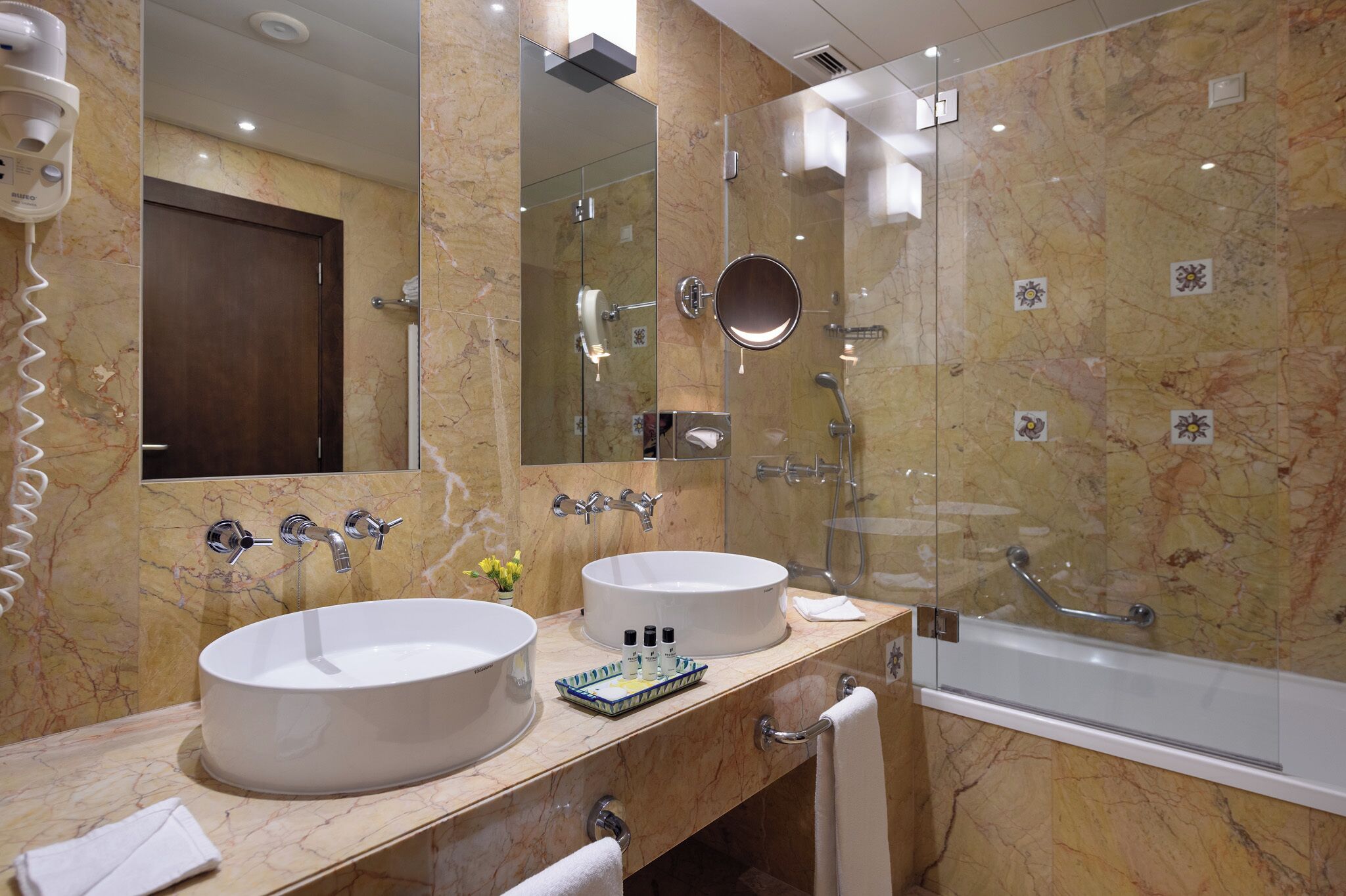 A bathroom with two sinks, a glass shower enclosure, and a large mirror.