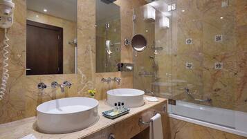 Un baño con dos lavamanos, cabina de ducha con mampara de vidrio y un espejo grande.