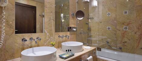 A bathroom with two sinks, a glass shower enclosure, and a large mirror.