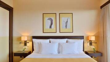 A hotel room with a large bed, two bedside tables with lamps, and two framed pictures on the wall.