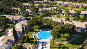 An aerial view of a resort with multiple bungalow-style accommodations, a central swimming pool, and surrounding greenery. - Pestana Vila Sol Golf - Vilamoura (Loulé)