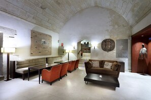 Un vestíbulo amplio con un techo alto en arco, una zona de estar con sofá y sillones, una mesa de centro y un reloj montado en la pared.