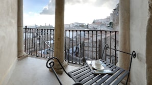 A balcony with a bench and a cup, overlooking a historic cityscape with buildings and a clear sky. - Eurostars Palacio Santa Marta (Trujillo)