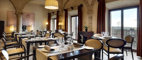 Un restaurante con varias mesas dispuestas para comer, que presenta una decoración clásica con arcos y ventanas amplias.