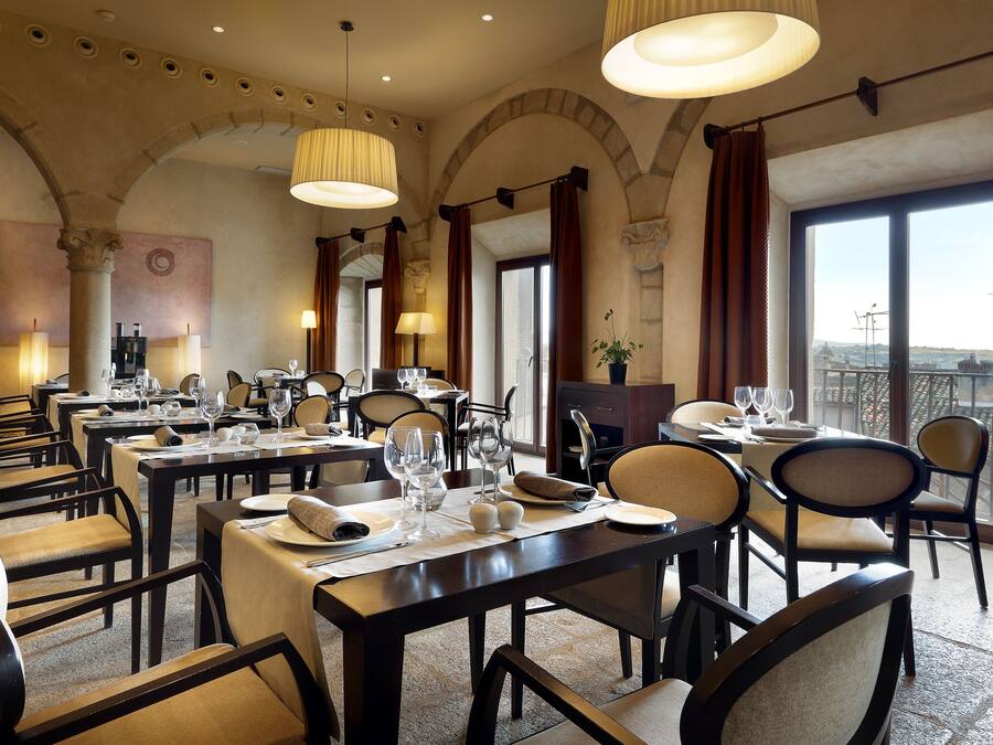 Un restaurante con varias mesas dispuestas para comer, que presenta una decoración clásica con arcos y ventanas amplias.