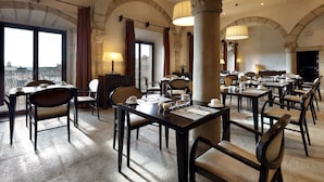 A dining area with tables and chairs, large windows, and a view of the city. - Eurostars Palacio Santa Marta (Trujillo)