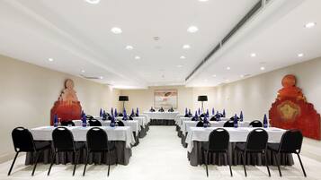 A conference room with multiple tables, black chairs, and blue centerpieces.