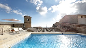 A swimming pool with lounge chairs and a tower structure in the background. - Eurostars Palacio Santa Marta (Trujillo)