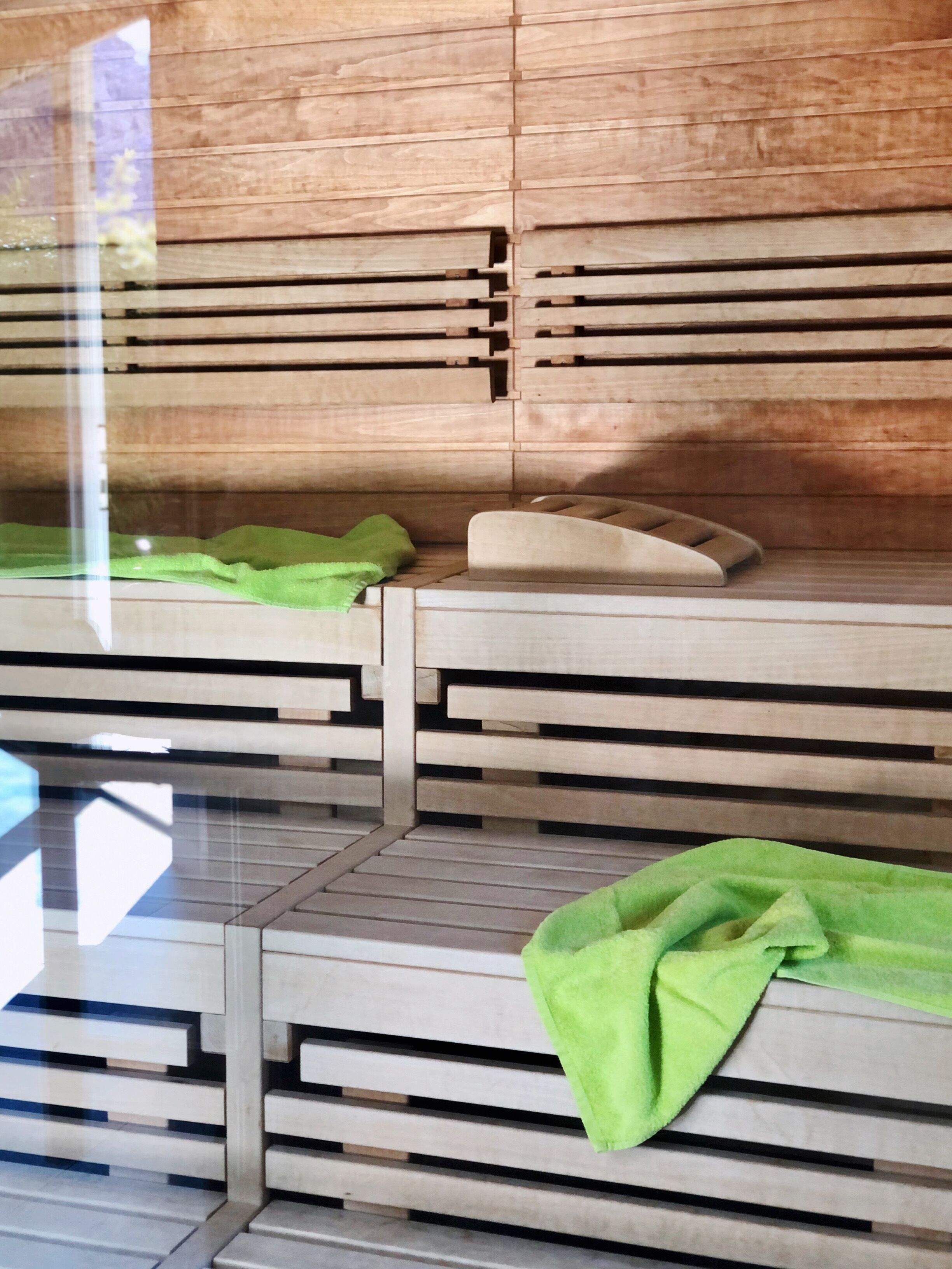 A modern room with a wooden slatted wall design, a green towel, and a beige pillow on a flat surface.