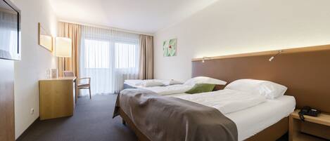 Una habitación de hotel con dos camas, un escritorio, una silla y un teléfono.