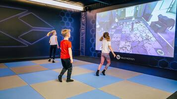 A group of children playing a video game in a room with a large screen displaying a game interface.