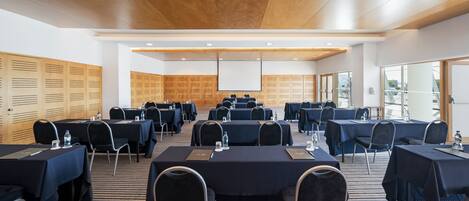 A conference room with multiple tables and chairs, equipped with water bottles and nameplates.