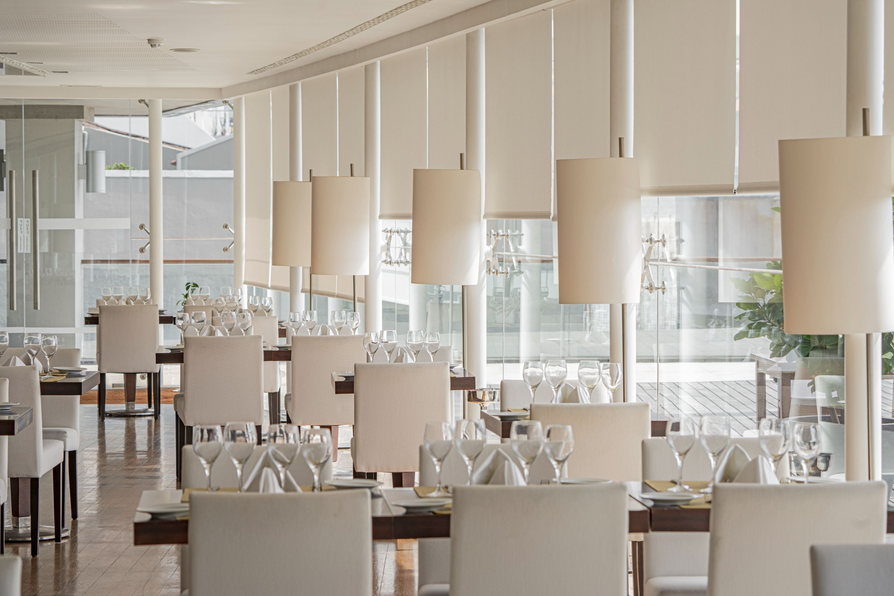 A modern restaurant with white furniture and large windows.