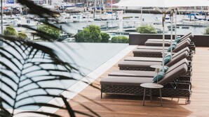 A rooftop lounge area with sun loungers and a view of a marina. - Hotel Marina Atlântico (Ponta Delgada)