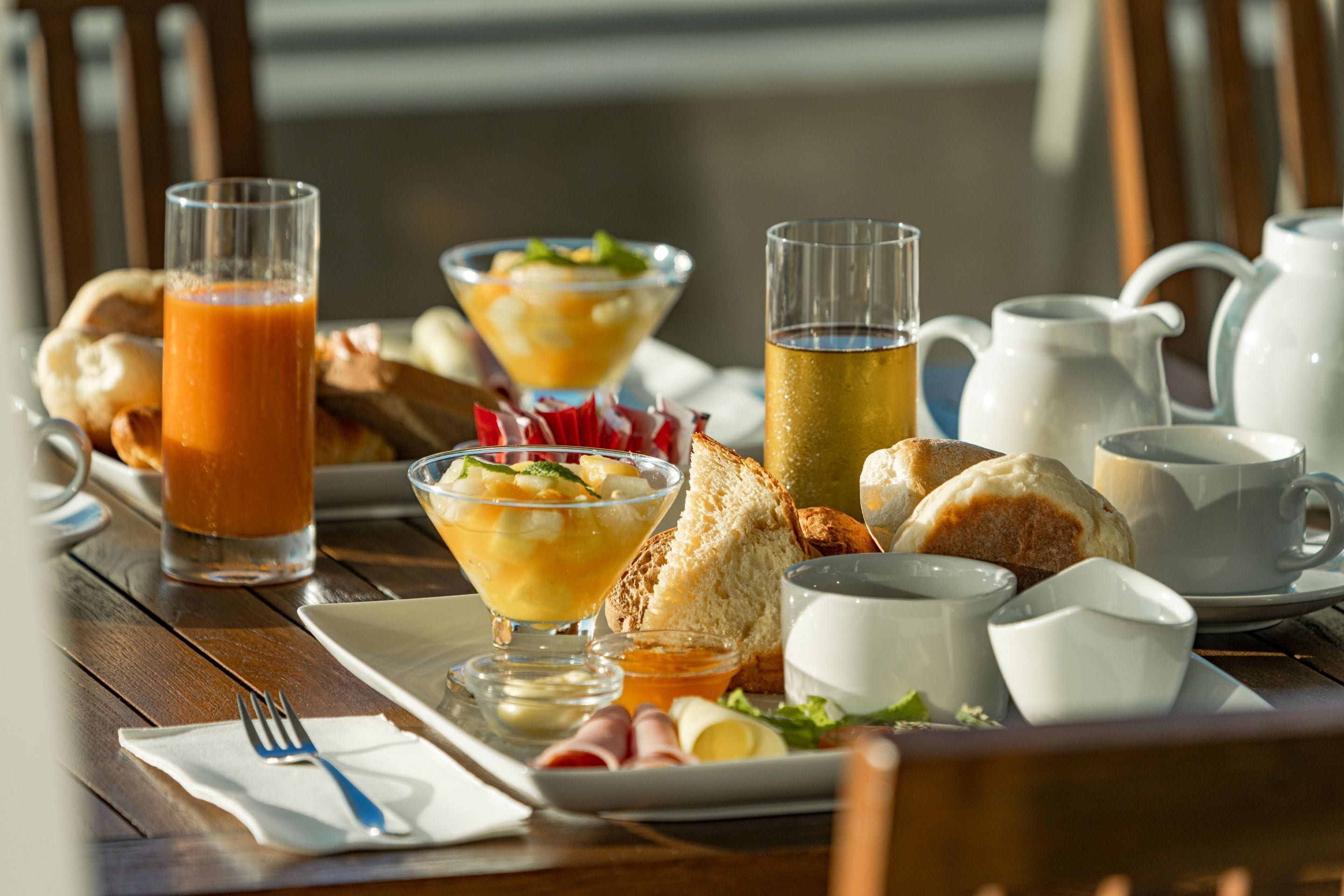 Une table en bois dressée pour le petit-déjeuner, avec une variété d’aliments et de boissons.
