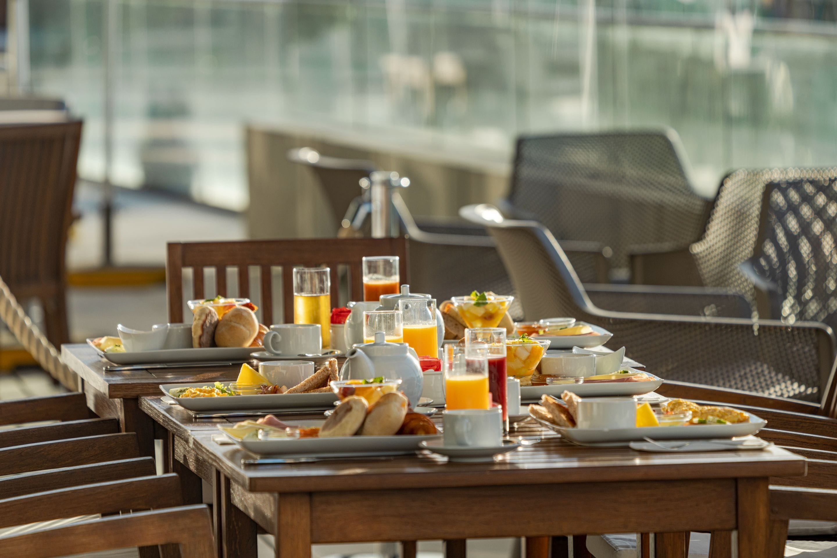 A breakfast table set with various dishes, drinks, and a pitcher of orange juice.