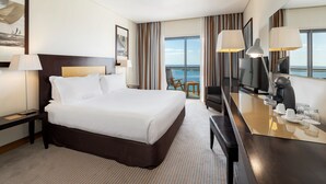 A hotel room with a large bed, a desk with a TV, and a view of the sea. - Hotel Marina Atlântico (Ponta Delgada)